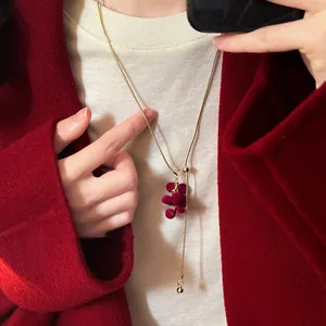 Close-up of a red flocked grape tassel necklace with an adjustable gold chain