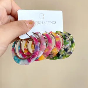 Detailed view of vibrant multicolored retro acetate hoop earrings with silver needles.