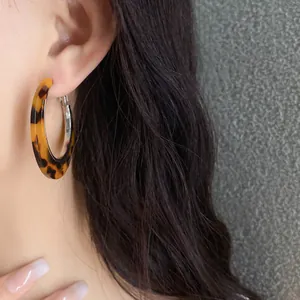 Detailed macro view of vintage leopard print acetate hoop earrings worn on model's ear