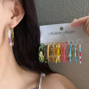 Detailed view of colorful acetate hoop earrings featuring vibrant marble patterns and gold accents
