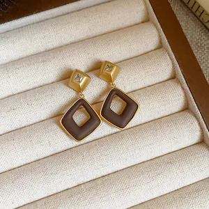 Vue détaillée de boucles d'oreilles géométriques marron vintage dans un écrin à bijoux