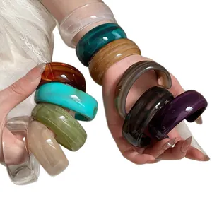 Handmade colorful acrylic open bangles with marble textures shown on a female hand
