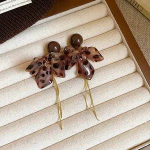 Gros plan de boucles d'oreilles fleur léopard avec longs pompons dorés dans un plateau