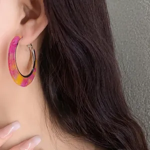 Detailed view of a stylish colorful marble acetate hoop earring worn on a model ear