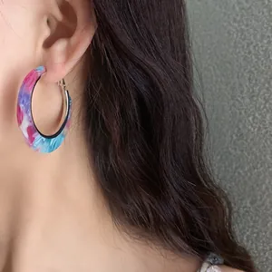 Close-up of marbled acetate hoop earring with vibrant blue and pink patterns