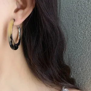Close-up view of a model wearing vintage acetate leopard print hoop earrings with silver pins