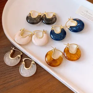 Macro view of geometric resin hoop earrings in various marble colors on a white tray.