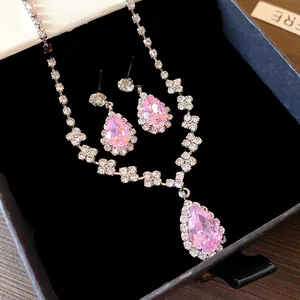 Dettaglio macro di collana e orecchini con zircone rosa a goccia in scatola regalo