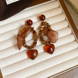 Vue détaillée des boucles d'oreilles cœur ambre style Maillard avec fleurs en tissu