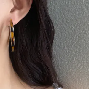 Detailed close-up of a vintage leopard print acetate hoop earring worn on a model's ear