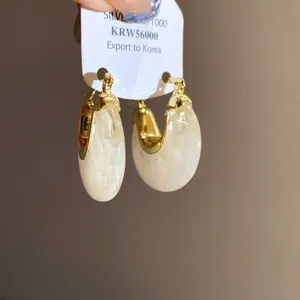 Detailed macro view of elegant gold and cream marble resin hoop earrings on white display card