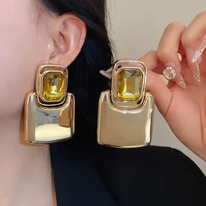 Statement square metal stud earrings featuring a large yellow gemstone and silver needle.