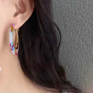 Close-up detail of vintage style colorful marbled acetate hoop earrings worn on ear