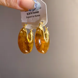 Detailed close-up view of vintage resin hoop earrings with amber texture and gold accents
