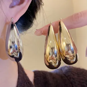 Vue détaillée de boucles d'oreilles goutte métalliques avec une finition brillante