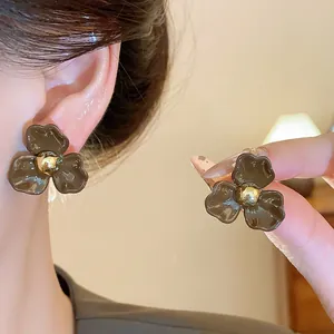 Vue détaillée de boucles d'oreilles fleurs en émail marron vintage avec perle d'or.