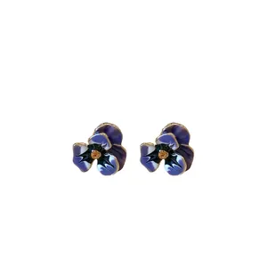 Purple and blue enamel flower stud earrings with a crystal center on a white background.