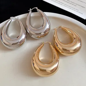 Gros plan de boucles d'oreilles créoles gouttes d'eau or et argent sur plateau