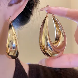Vue détaillée de grandes boucles d'oreilles dorées en forme de goutte au fini miroir
