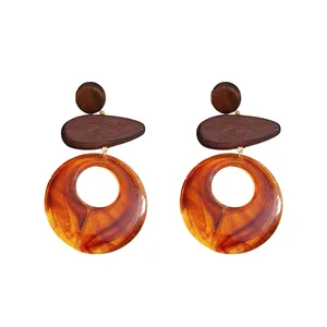 Elegant ethnic style drop earrings with wooden studs and amber resin circular pendants.