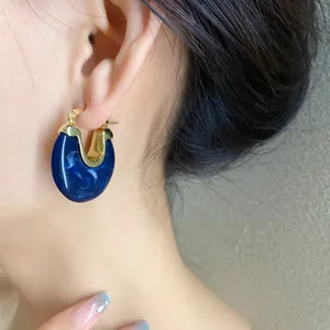 Detailed macro view of a vintage-style blue resin geometric hoop earring worn
