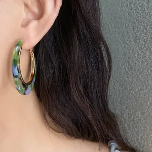 Detailed view of vintage acetate hoop earring with colorful marble pattern worn by a model