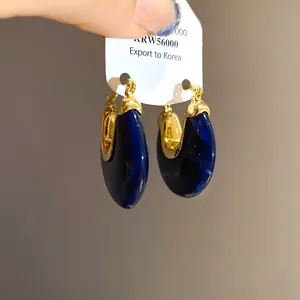 Close-up of vintage dark blue marbled resin hoop earrings with gold finish