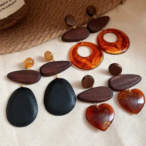 Detailed shot of ethnic style wooden earrings with amber resin heart and ring pendants.