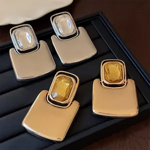 Detailed view of oversized square metal stud earrings with rectangular crystals