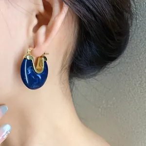 Close-up macro detail of a vintage blue marbled resin geometric hoop earring worn on ear