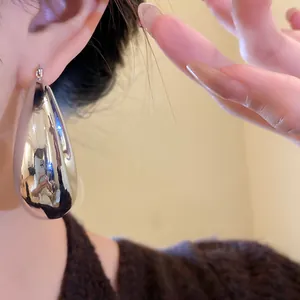 Gros plan détaillé des boucles d'oreilles goutte argentées avec une finition polie.