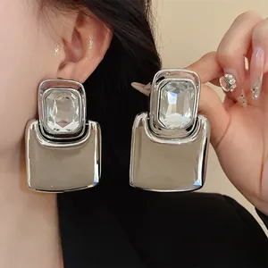Close-up of oversized square silver earrings with large clear rhinestones in chic style