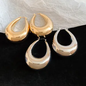 Gros plan de boucles d'oreilles créoles larmes or et argent sur fond noir élégant.