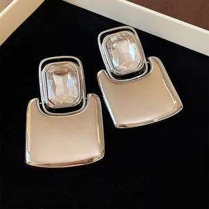Detailed macro view of silver-tone square metal stud earrings with large clear crystal facets