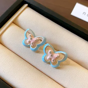 Detail view of light blue and pink enamel butterfly stud earrings with small crystals