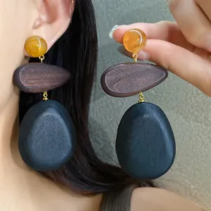 Close-up of retro ethnic style wooden teardrop earrings worn by an elegant Asian model