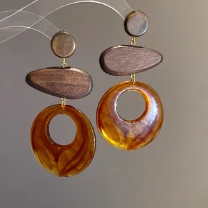 Close-up of retro wooden and amber resin ring dangle earrings with silver needle
