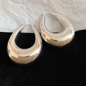 Vue macro de boucles d'oreilles argentées en forme de goutte sur un fond contrasté