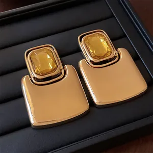 Close-up of vintage gold-tone rectangular earrings with amber yellow gemstones.