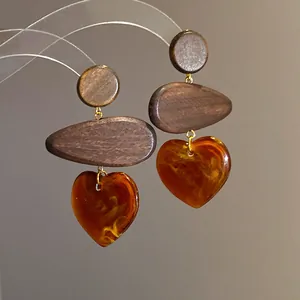 Detailed view of ethnic style wooden earrings featuring amber-colored resin heart pendants
