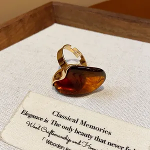 Close-up of a vintage amber resin oval open ring on a textured display card