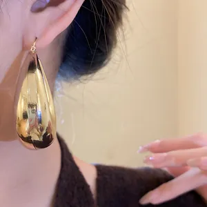 Vue détaillée de boucles d'oreilles goutte d'eau dorées avec finition métal poli.