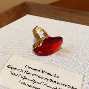 Close-up of a vintage-style red resin oval open ring with a gold adjustable band.