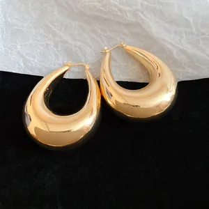 Gros plan de boucles d'oreilles créoles dorées oversize en forme de goutte d'eau