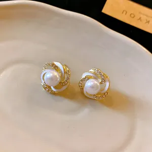 Detailed view of elegant floral stud earrings with white enamel and shimmering pearls.