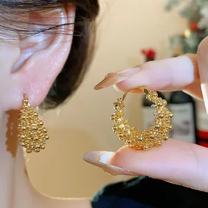 Close-up view of 18k gold-plated textured hoop earrings showing intricate granular detail.