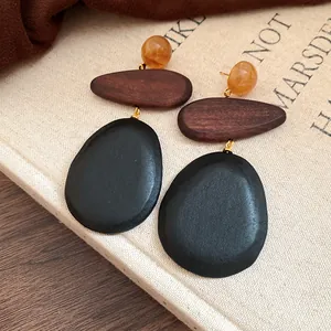 Close-up detail of minimalist ethnic statement earrings with wood and black stone texture