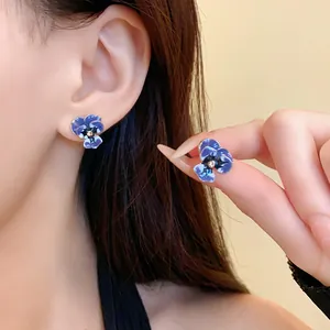 Detailed view of blue pansy flower stud earrings with enamel finish and crystal center
