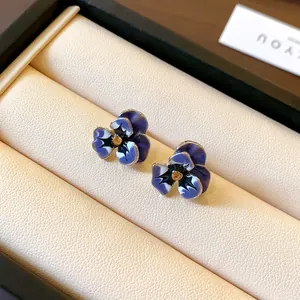 Macro detail of elegant pansy flower stud earrings with enamel petals and crystal centers