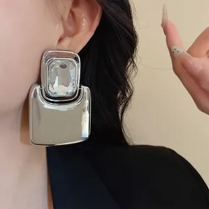Close-up detail of silver oversized geometric stud earring with clear crystal.